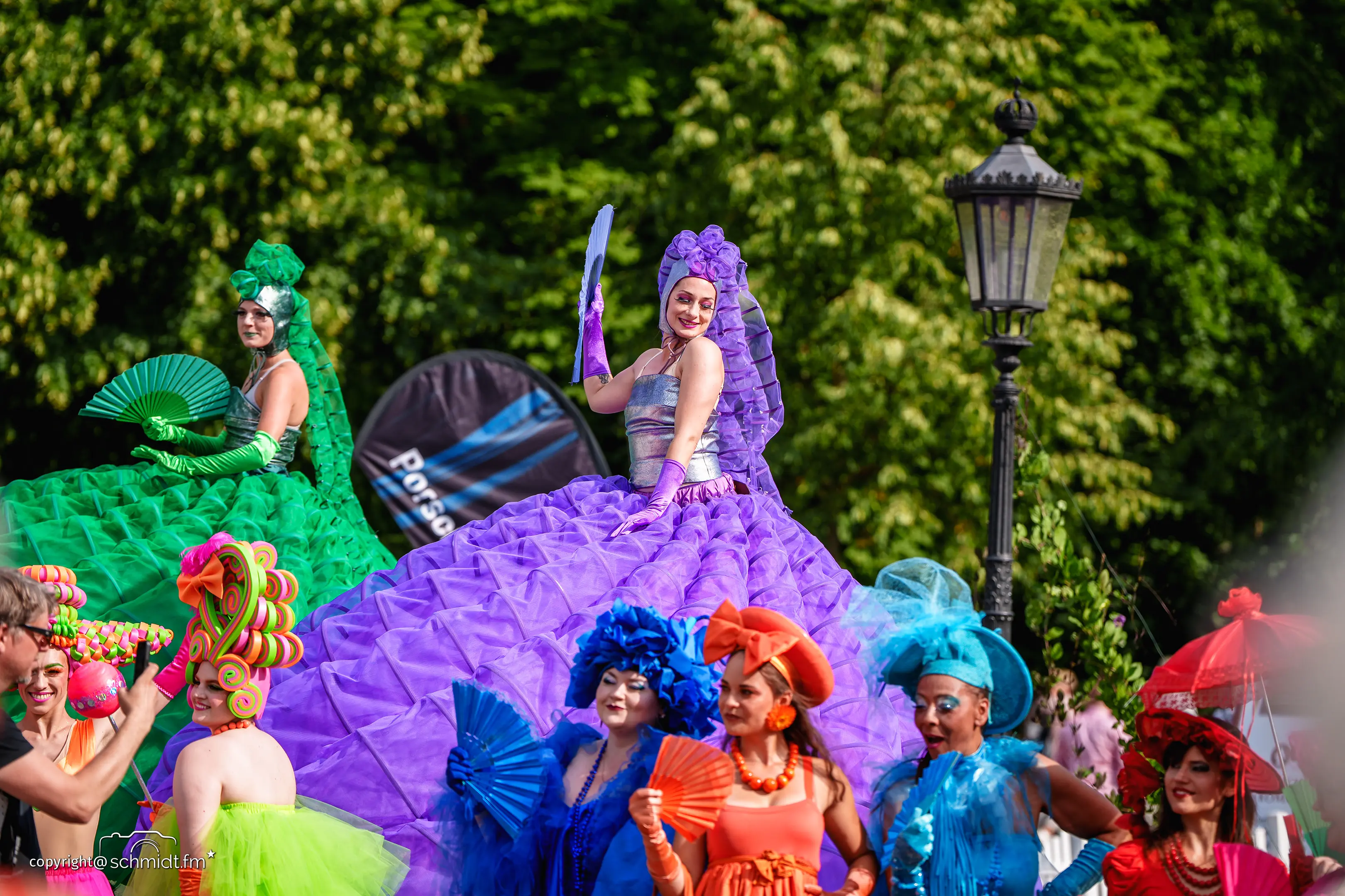 Frauen auf Stelzen in großen, bunten Kostümen